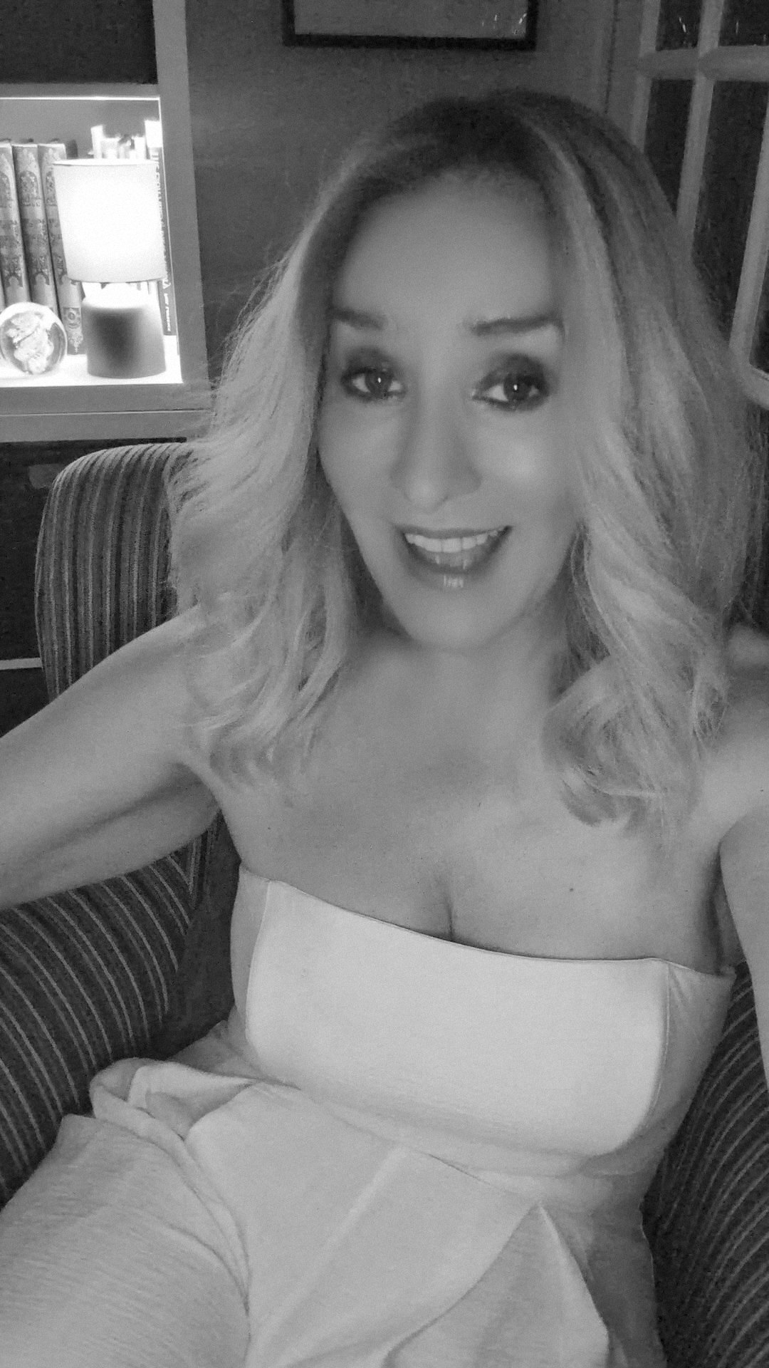 Black-and-white photograph of Stevie in a strapless top in a bar, laughing