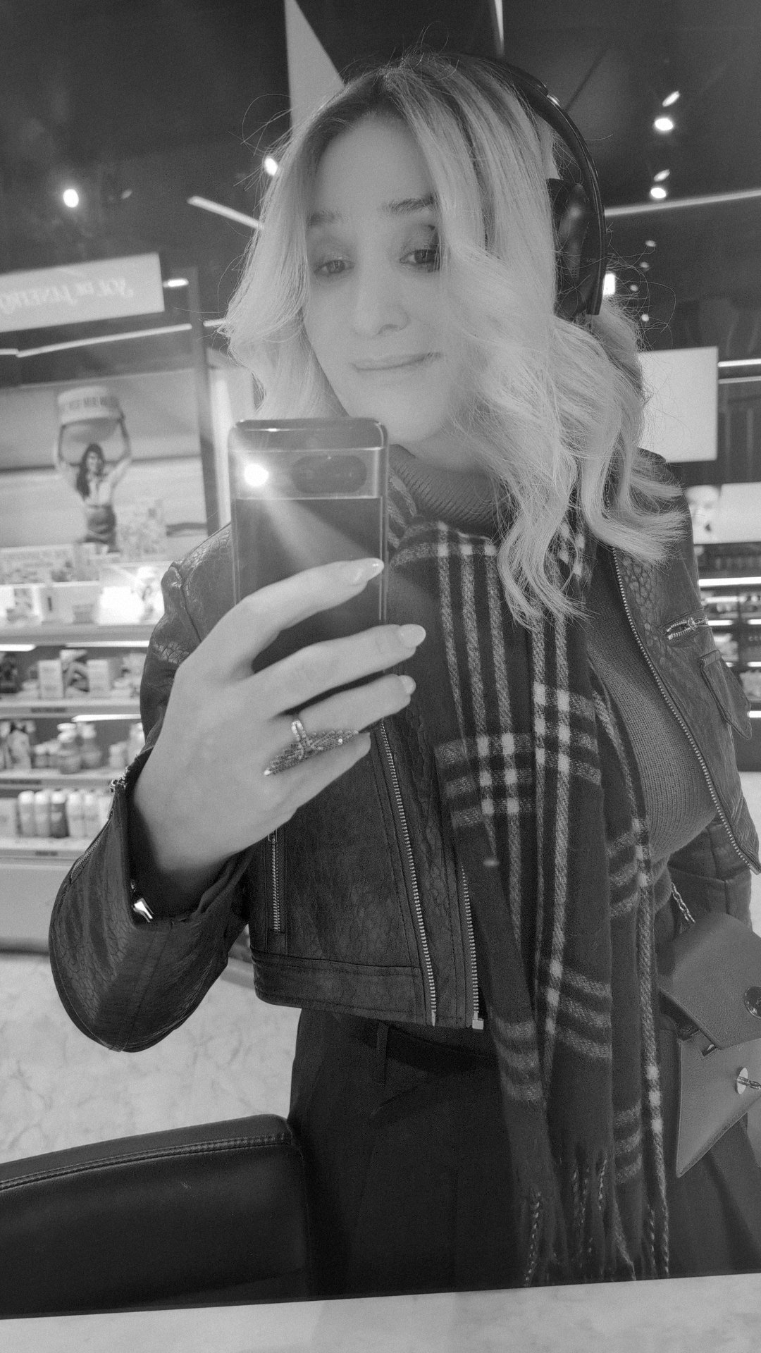 Black-and-white mirror selfie of Stevie in a leather jacket and checked scarf, headphones on